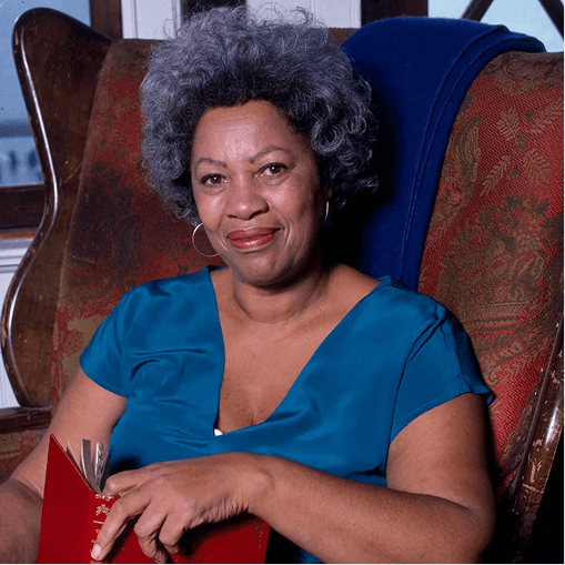 Woman in a blue top seated in an armchair with a red book