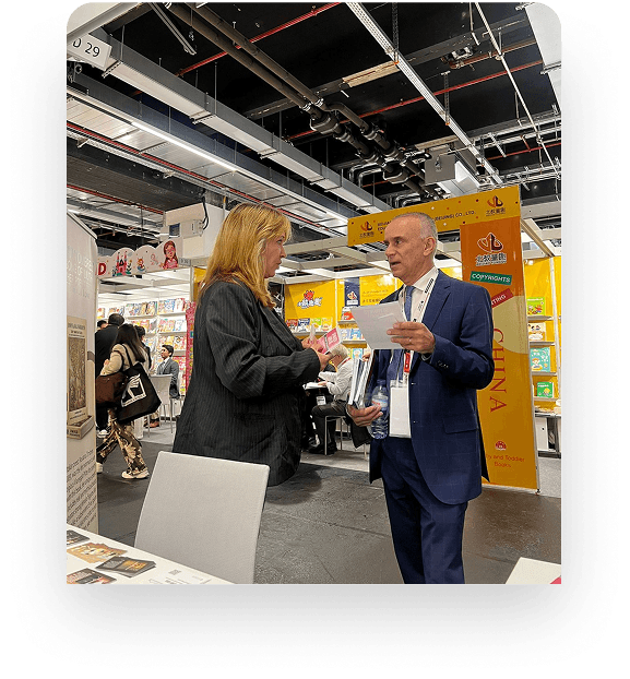 Two people talking beside a book display at a fair